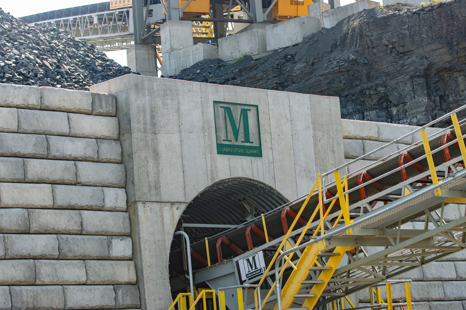 Conveyor system running through a concrete tunnel portal at a stone quarry