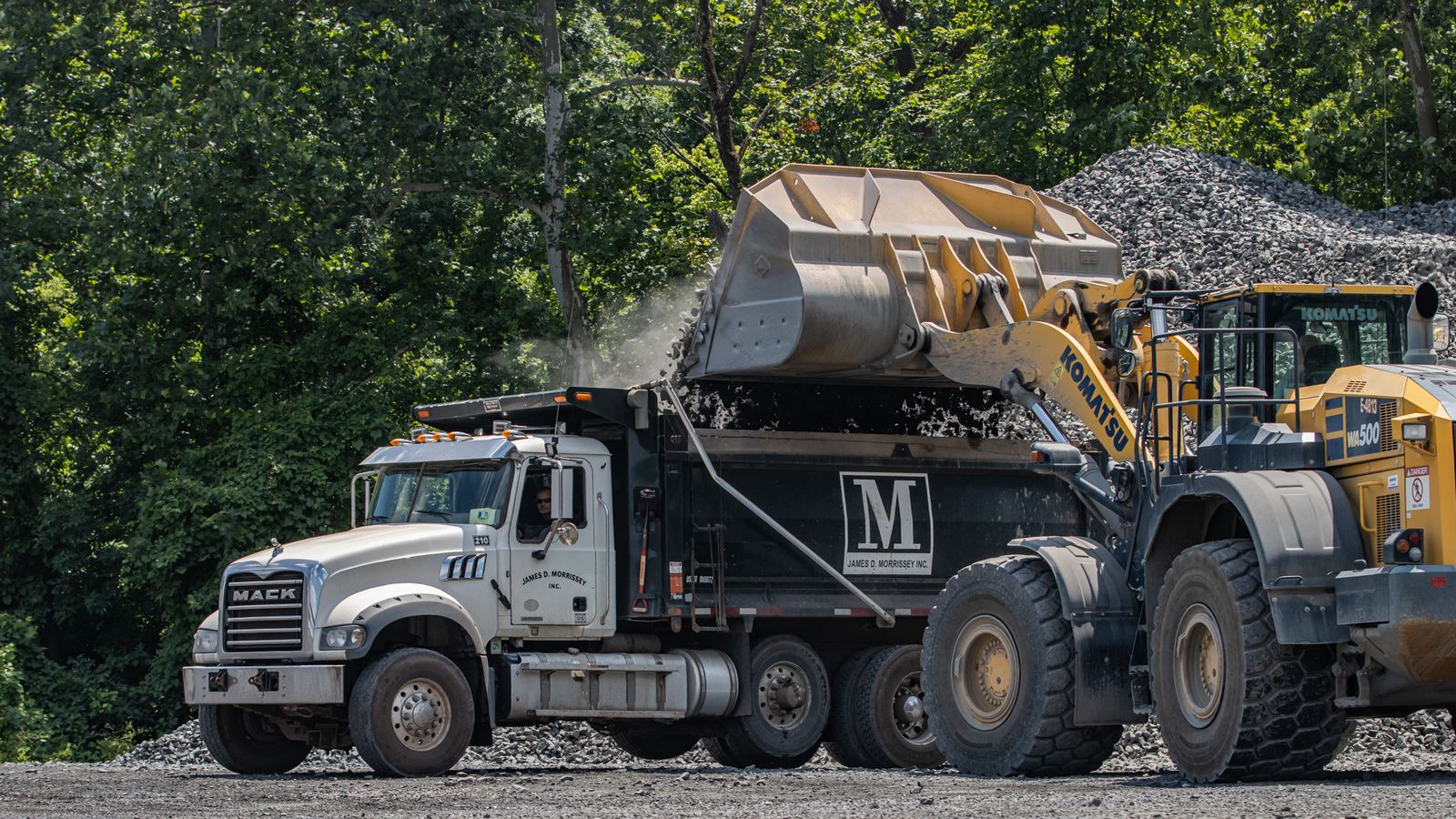 Komatsu WA500 wheel loader loading a Mack dump truck with aggregate at a quarry